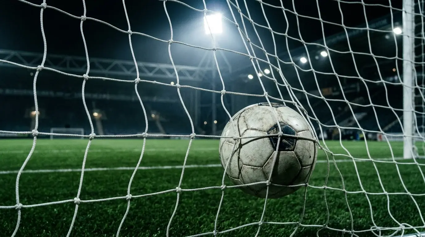 Ett fotbollsmål i närbild med nätet upplyst av strålkastare